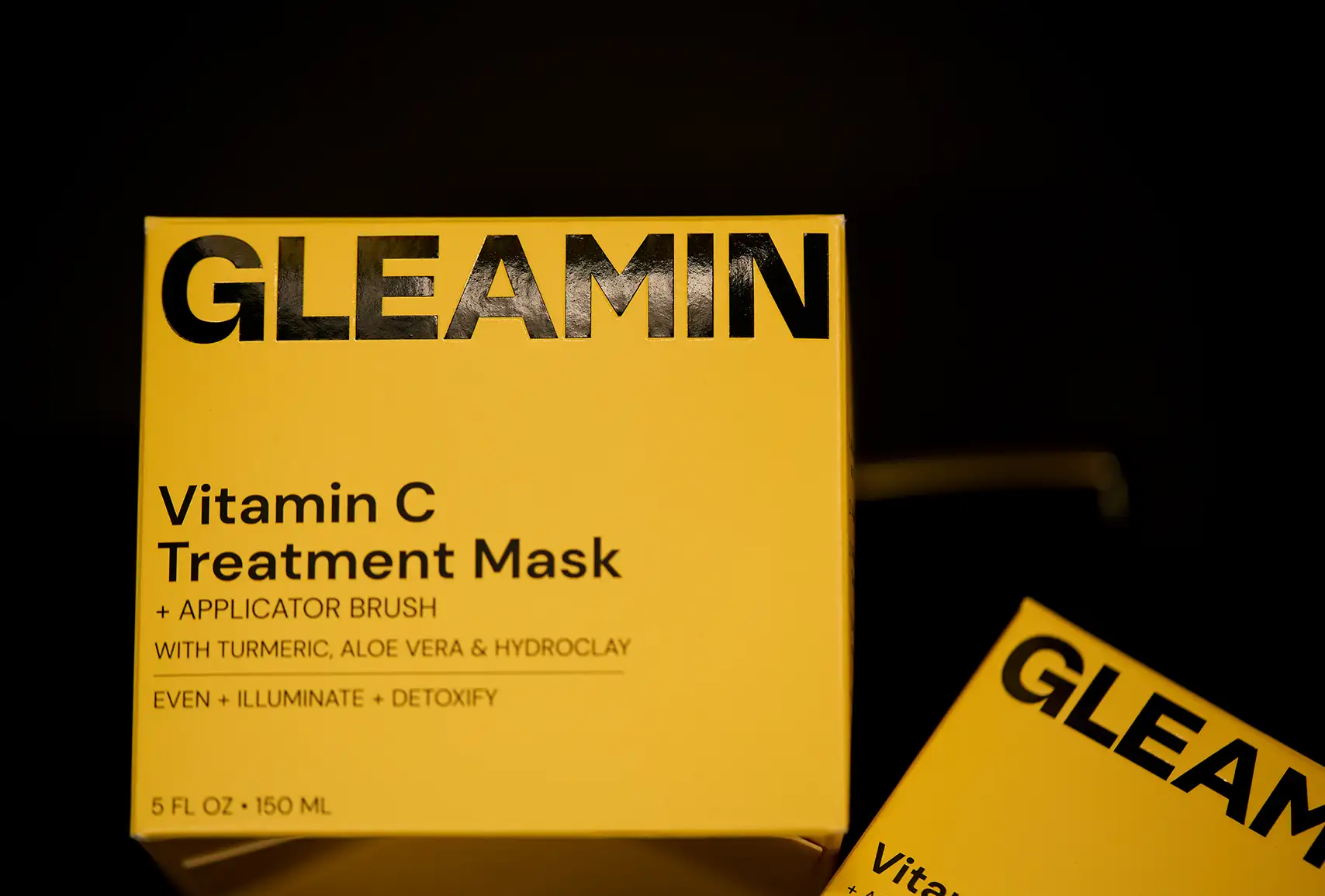 Close-up of a yellow product packaging box with a metallic letter ‘G’ on top and the word ‘GLEAMIN’ printed vertically on the side.