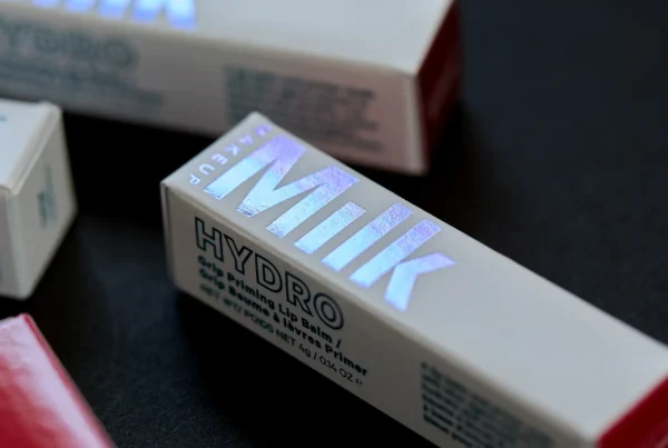 Close-up of Milk Makeup Hydro Grip Priming Lip Balm packaging with iridescent holographic lettering on a light-colored box.