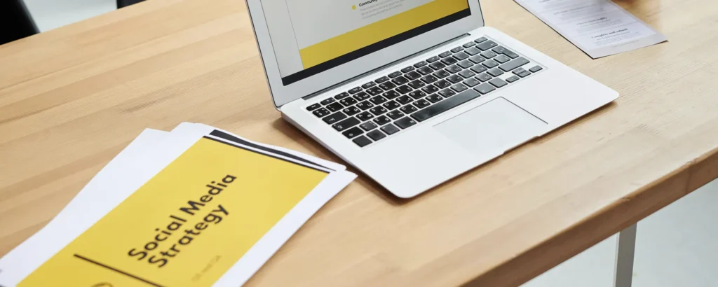 Desk with laptop and printed powerpoint deck.